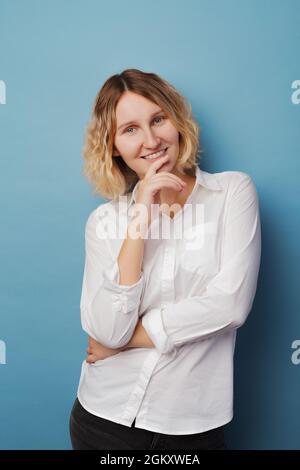 Die Frau dachte, sie rieb sich mit der Hand das Kinn. Lady lächelt und posiert im Studio. Stockfoto