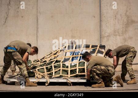 US Air Force Airmen, die dem 721. Aerial Port Squadron zugewiesen wurden, sichern eine Palette an Ausrüstung im 2021 Multi-Capable Airman Rodeo auf dem Ramstein Air Base, Deutschland, 23. Juli 2021. Die Airmen führten Operationen durch, darunter Palettiergeräte, einen 60K-Lader für Flugzeuge durch einen Hindernisparcours und das Zurückrufen von 20 Gegenständen aus dem Gedächtnis, nachdem sie eine physische Herausforderung bewältigt hatten. Stockfoto