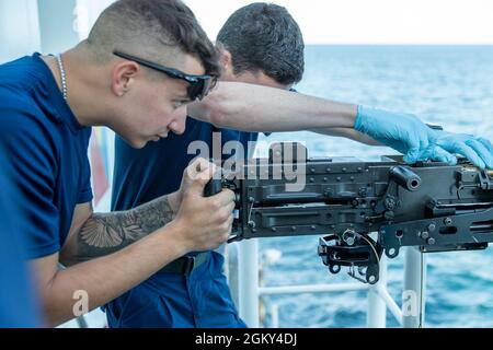 CAPE COD, Ma – (Juni 24 2021) Seaman Cory Conlan (links) und Seaman Kevin Flynn, beide Mitglieder des weißen Mittelausdauerklassers USCGC Escanaba, lernen an Bord, das 50-mm-Maschinengewehr ohne Abschuss zu bedienen. Die Schulung hilft, die Einsatzbereitschaft bei Bedarf zu gewährleisten. Stockfoto