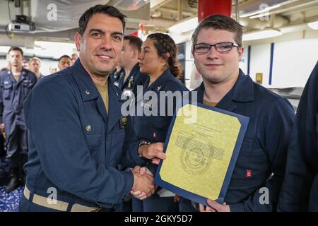 MITTELMEER (25. Juli 2021) Kommandant Cmdr. John D. John, links, überreicht einen Anerkennungsbrief an den Feuerwehrmann Seaman Zakary Letney an Bord des Arleigh Burke-Klasse Lenkrakenzerstörers USS Ross (DDG 71), während er am 25. Juli 2021 im Mittelmeer unterwegs war. Ross, der im spanischen Rota stationiert ist, ist auf Patrouille im Einsatzgebiet der Sechsten Flotte der USA, um regionale Verbündete und Partner sowie nationale Sicherheitsinteressen der USA in Europa und Afrika zu unterstützen. Stockfoto