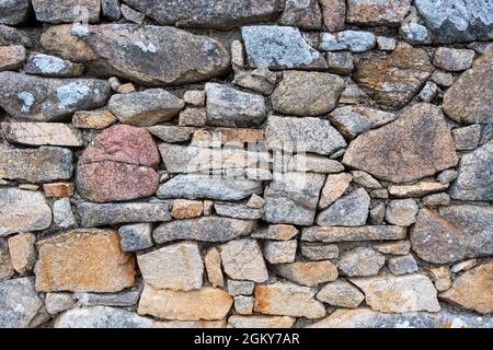 Detail einer Mauer aus unregelmäßigen und bunten Steinen in der Bretagne, Frankreich Stockfoto