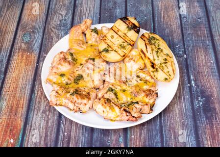 Gegrilltes Huhn ohne Knochen mit Honig-Senfsauce und halbierte Bratkartoffel mit Petersilie und Olivenöl Stockfoto