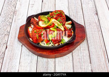 Das beliebteste asiatische Tandoori-Stil Braten Huhn Rezept mit Zwiebeln, Paprika, Tomaten und gehackten frischen Cilantro auf Gusseisen Tablett Stockfoto