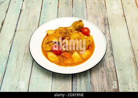 Würziger gelber Chicken Curry, zubereitet von einem thailändischen Koch mit Kirschtomaten, Trauben und geschmorten Kartoffeln Stockfoto