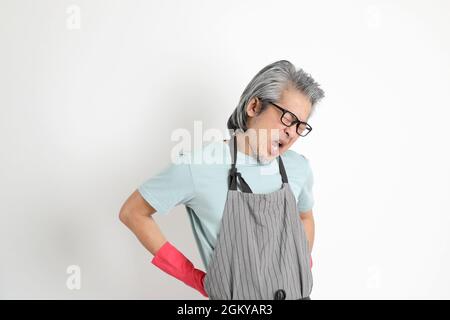 Die ältere asiatische Haushälterin, die auf weißem Hintergrund steht. Stockfoto