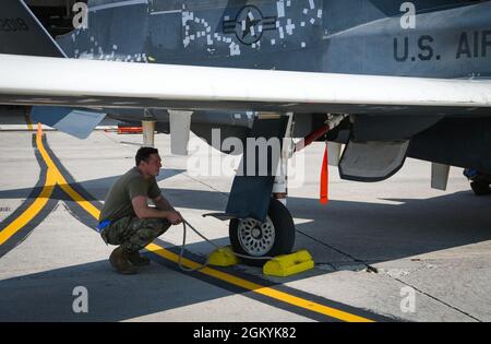 Der Senior Airman Riley McAuliffe, Spezialist für Luftfahrtelektronik der 319. Luftwartungssequadron, bereitet sich darauf vor, die Unterlegkeile vom EQ-4 Block-20 Global Hawk zu ziehen, bevor er in einen Hangar auf der Grand Forks Air Force Base, N.D., geschleppt wird, 29. Juli 2021. Die Abschlusszeremonie und die Lagerung der Block-20-Flugzeuge erforderten die Koordination und Zusammenarbeit verschiedener Berufsfelder und Flugzeuge. Stockfoto