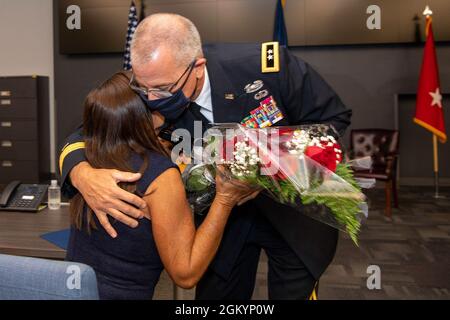 Der Generalmajor Keith Waddell, Adjutant General der Nationalgarde von Louisiana, umarmt seine Frau Lisa, als er ihr einen Strauß roter Rosen als Anerkennung für ihre unerschütterliche Unterstützung während seiner Beförderungszeremonie im Büro des Gouverneurs für innere Sicherheit und Notfallbereitschaft am 30. Juli 2021 überreicht. In Baton Rouge, La. Maj. Gen. Waddell ist der Vater von drei Kindern und der Großvater von drei. Stockfoto