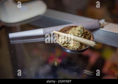 Nahaufnahme eines Gelenks, der mit Marihuana gerollt wurde und auf rohes Marihuana gelegt wurde. Stockfoto