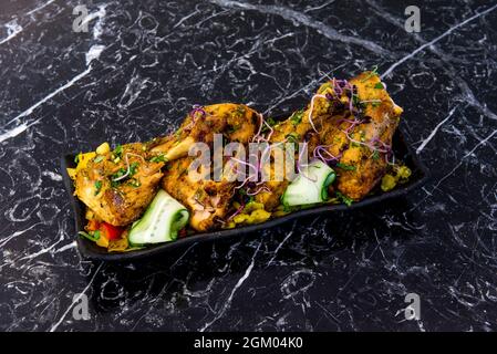 Tablett mit gebratenem indischem Huhn mit Tandoori-Rezept mit Gemüse und asiatischen Gewürzen auf schwarzem Marmortisch Stockfoto