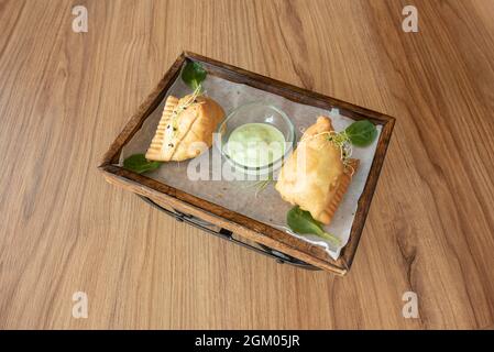 Gebratene Samosas gefüllt mit Gemüse mit Bohnensprossen auf der Oberseite und indischer grüner Sauce zum Eintauchen Stockfoto