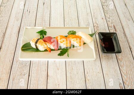 Gemischtes Sushi-Mixtablett mit Lachs Nigiri, Uramaki california Roll, Thunfisch und Avocado Maki, Nori-Algen, Reisnudeln, Wasabi und Ginseng Stockfoto