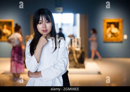 Chinesische junge Frau in der Nähe der Bildersammlung im Museum Stockfoto