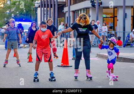Eine Frau hilft zwei Kindern, während Roll Mobile, 10. September 2021, in Mobile, Alabama, das Rollschuhlaufen zu lernen. Die Skate Night findet monatlich statt. Stockfoto
