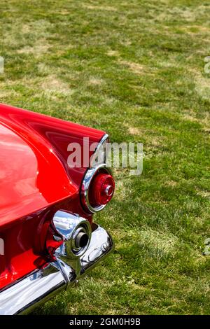 Die rechte hintere Ecke eines klassischen roten Ford Thunderbird Sportwagens aus dem Jahr 1955 zeigt das Auspuffendrohr durch die Bumperette. Stockfoto