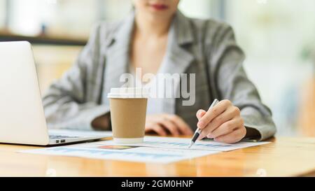 Eine kleine Aufnahme einer schönen jungen Geschäftsfrau, die beim Arbeiten am Schreibtisch vor dem Laptop Papierkram macht. Stockfoto