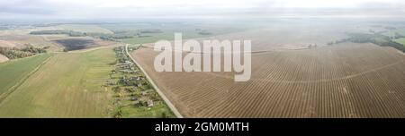 Panorama-Luftaufnahme der Landschaft mit Dorf zwischen landwirtschaftlichen Feldern im Herbst Morgennebel Stockfoto