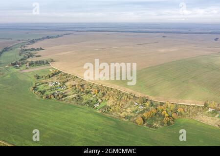 Blick auf die Landschaft mit Dorf zwischen kultivierten Feldern am nebligen Morgen. Panorama Drohne Foto. Stockfoto
