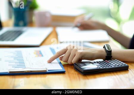 Nahaufnahme einer Geschäftsfrau oder Buchhalterin, die mit dem Zeigefinger auf Finanztabellen, Verkaufsberichte und Geschäftsunterlagen im Büro zeigt Stockfoto