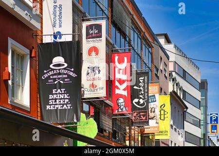 Karlsruhe, Deutschland - August 2021: Banner von Geschäften und Restaurants, die an Fassaden hängen Stockfoto