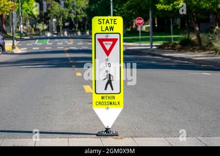 Staatliche Gesetz Rendite für Fußgänger innerhalb Crosswalk reboundable Straßenschild. Stockfoto