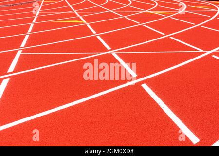 Allwetter-Laufstrecke. Weiße durchgehende Linien kreuzen sich auf roten Gummirassen, selektiver Fokus. Rennkurve auf Laufbahnoberfläche. Stockfoto