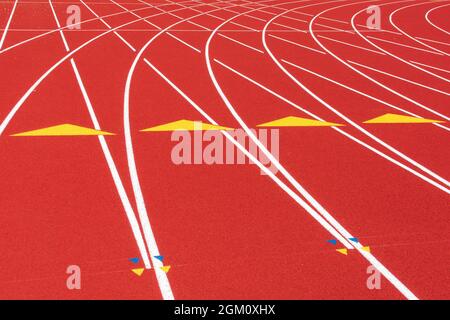 Weiße Linien, gelbe Dreiecke und Hürdenmarkierungen auf der Kurve der wetterbedingten Gummi-Laufstrecke. Stockfoto