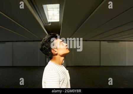 Seitenansicht eines hübschen jungen Mannes, der sich bereit für die Dreharbeiten in der Tiefgarage ausatmet Stockfoto