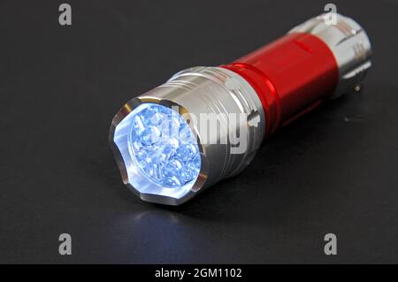 Beleuchtete LED-Taschenlampe vor einem schlichten Hintergrund. Stockfoto