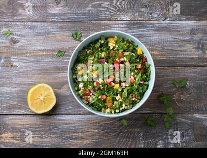 Original orientalischer Salat Tabbouleh mit Kohlkalk, Petersilie, Bulgur, Tomaten und roten Zwiebeln auf einem Holztisch, Draufsicht. Gesunde hausgemachte Speisen Stockfoto