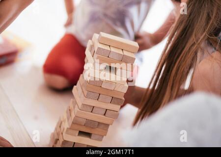 Verschwommene Kinderhände spielen Spiel mit Turm aus Holzblöcken Stockfoto