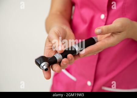 Arzt in rosa medizinischen Kleidern hält Otoskop in den Händen. Medizinische Forschung. Vorsorgeuntersuchungen. Medizin und Versicherungen. Gesundheitsschutz. Mod Stockfoto