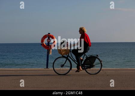 Frau sah, wie sie mit dem Fahrrad am Meer entlang fuhr. Stockfoto