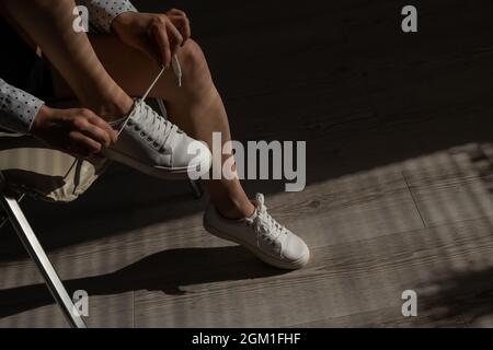 Frau zog neue weiße Leder-Sneakers an Stockfoto