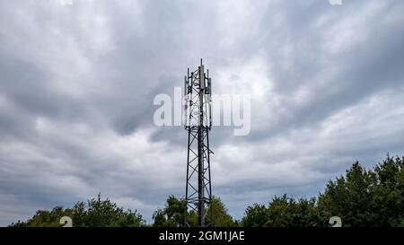 3G, 4G, 5G. Basisstation für Mobiltelefone Tower. Entwicklung des Kommunikationssystems im städtischen npn-Waldgebiet mit dunkelstürmischem grauem Himmel Hintergrund. Hochwertige Fotos Stockfoto