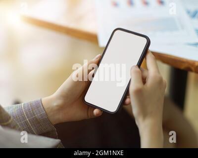 Nahaufnahme, die Hände der Frau halten das Smartphone mit leerem Kopierplatz für Ihre Werbeinhalte. Geschäftsfrau mit Mobiltelefon, während sie in Meeti sitzt Stockfoto