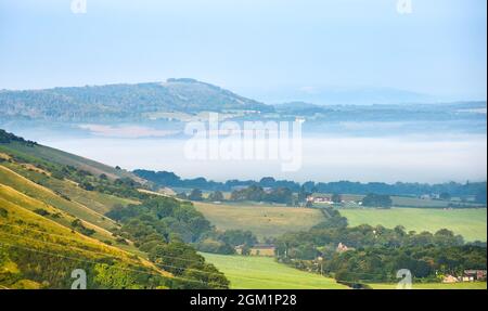 Brighton UK 16. September 2021 - am frühen Morgen liegt Nebel über der Landschaft unterhalb der South Downs, wenn die Sonne am Devils Dyke nördlich von Brighton aufgeht : Credit Simon Dack / Alamy Live News Stockfoto