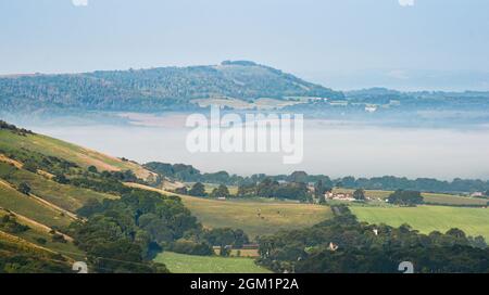 Brighton UK 16. September 2021 - am frühen Morgen liegt Nebel über der Landschaft unterhalb der South Downs, wenn die Sonne am Devils Dyke nördlich von Brighton aufgeht : Credit Simon Dack / Alamy Live News Stockfoto