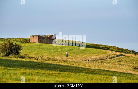 Brighton UK 16. September 2021 - ein frühmorgendlicher Hundespaziergänger genießt die warme Sonne am Devils Dike entlang des South Downs Way nördlich von Brighton : Credit Simon Dack / Alamy Live News Stockfoto