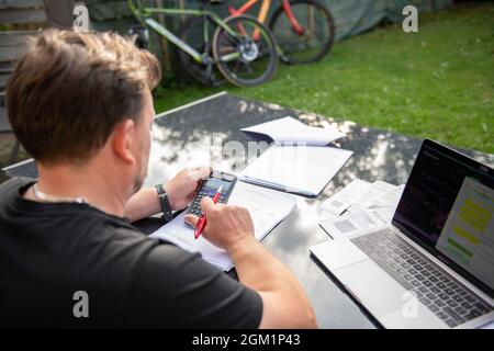 Fischbach, Deutschland. September 2021. Ein Mann sitzt zu Hause im Garten und arbeitet an seinem Rechner. Quelle: Silas Stein/dpa - ACHTUNG: Der Inhalt der Dokumente wurde unkenntlich gemacht (verpixelt)/dpa/Alamy Live News Stockfoto