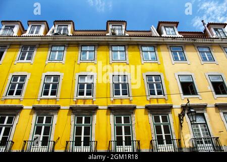 Farbenfrohe und majestätische alte Häuser in Lissabon. Alte Steinfassaden mit großen Fenstern im Frühling. Stockfoto