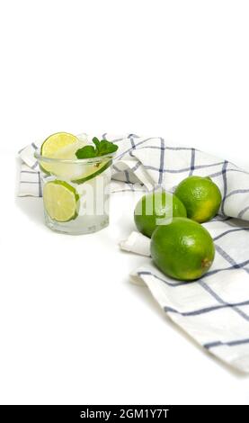 Schneiden Sie Kalk und Kalkwasser in einem Glas mit einem Strohhalm in Backpulver. Erfrischender Schuss auf weißem Hintergrund eines sommerlichen kühlenden Getränks mit Eis, Minze, Limette Stockfoto