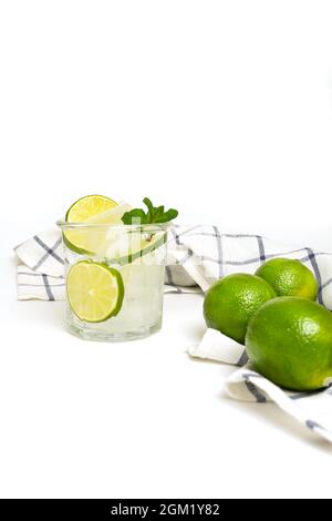 Schneiden Sie Kalk und Kalkwasser in einem Glas mit einem Strohhalm in Backpulver. Erfrischender Schuss auf weißem Hintergrund eines sommerlichen kühlenden Getränks mit Eis, Minze, Limette Stockfoto