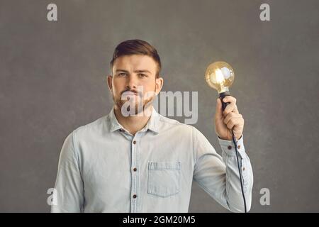 Ernst selbstbewussten Erwachsenen kaukasischen Mann hält beleuchtete Glühbirne Studio Schuss Stockfoto