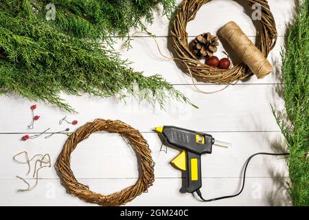 Machen Sie einen Weihnachtskranz mit Ihren eigenen Händen. Fichtenzweig, Weihnachtskranz und Geschenke auf weißem Holzhintergrund Stockfoto
