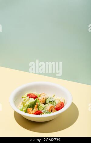 Caesar Salat mit Garnelen in weißen Teller auf gelb harten Schatten modern Stockfoto