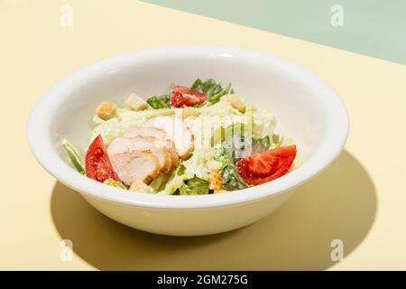 Caesar Salat in weißem Teller auf gelbem harten Schatten modern Stockfoto