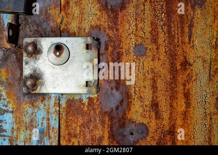 Alte rostige Metalltür, blau gestrichen, die durch Rost orange wird. Textur von Rissen und schält Farbe Stockfoto