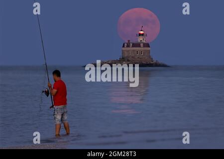 Buck Full Moon - der Buck- oder Thunder-Vollmond steigt hinter dem Penfield Reef Lighthouse in Fairfield, CT, auf. Es wurde 1874 erbaut und war eines der letzten Stockfoto