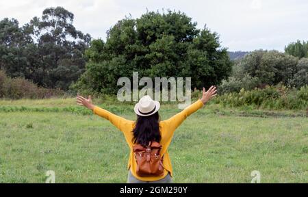 Erwachsene Frau mit einem Lederrucksack geht den Weg hinunter Stockfoto