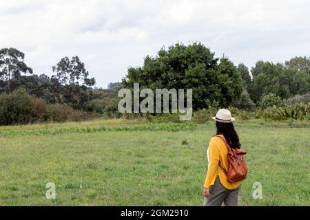 Erwachsene Frau mit einem Lederrucksack geht den Weg hinunter Stockfoto